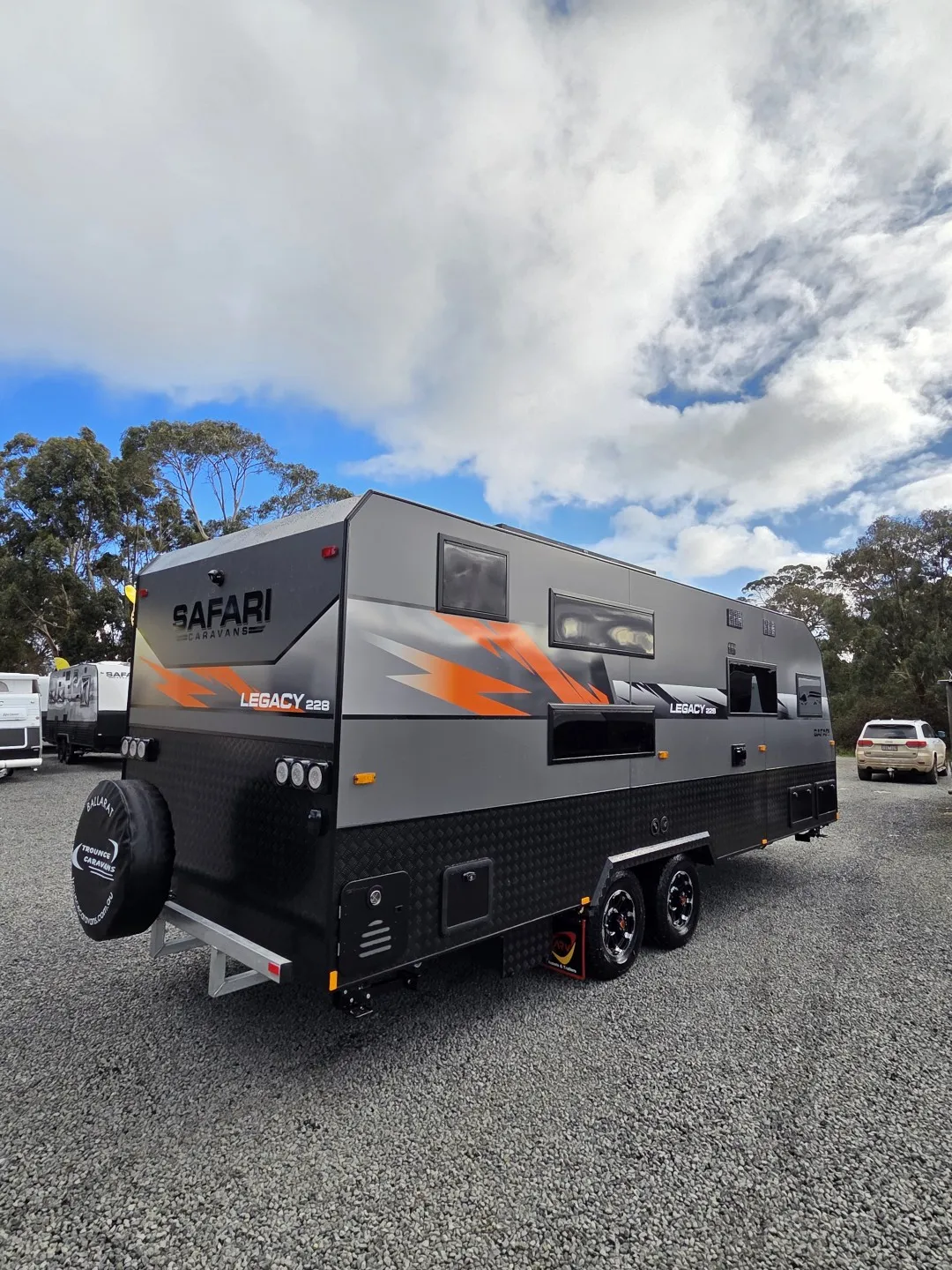 Safari Legacy 228 with orange graphics, rear three-quarter view on gravel